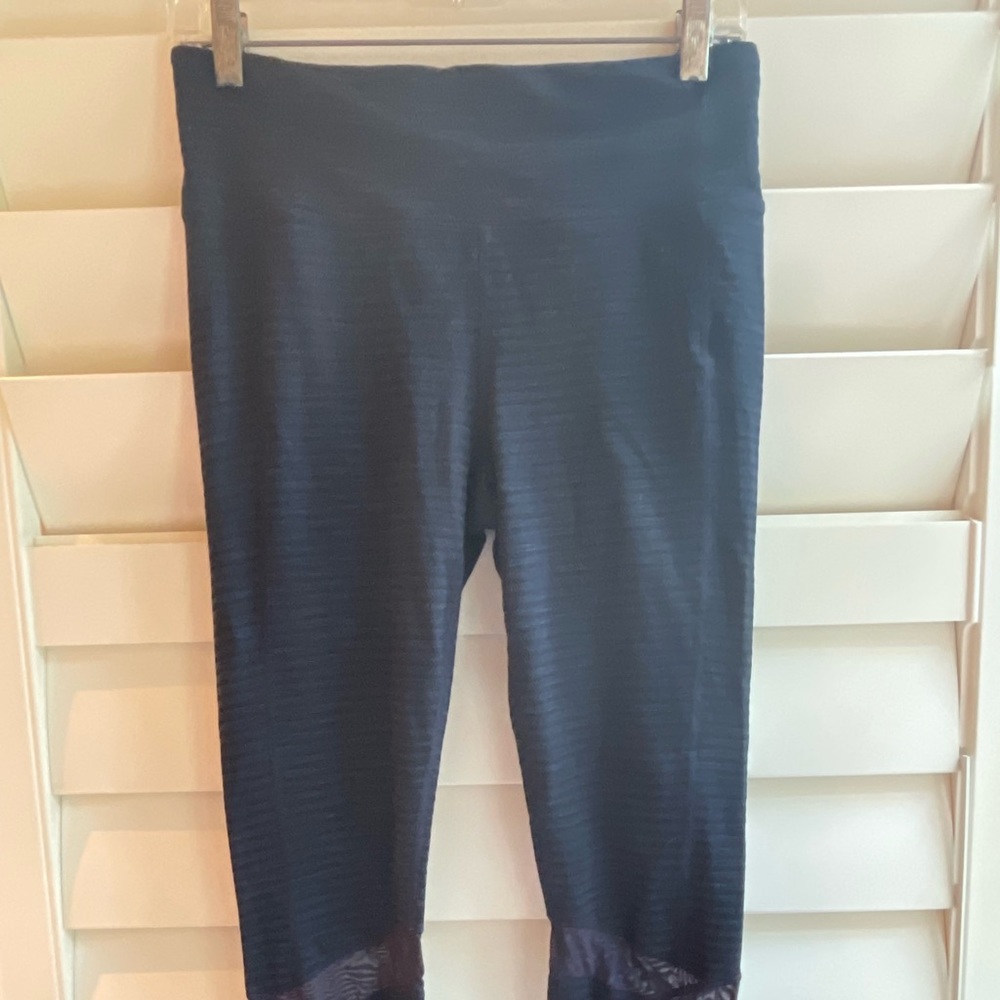 Women’s Athleta navy blue and black leggings with sheer cut out detail.